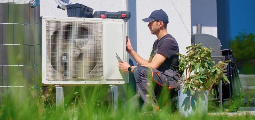 HVAC technician inspecting an outdoor air conditioning unit.