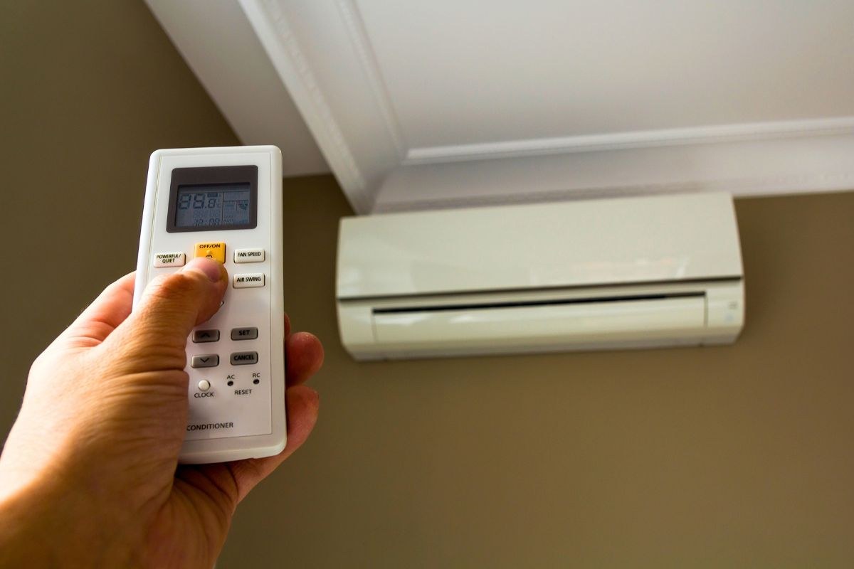 Homeowner adjusting the remote control of a wall-mounted air conditioner.