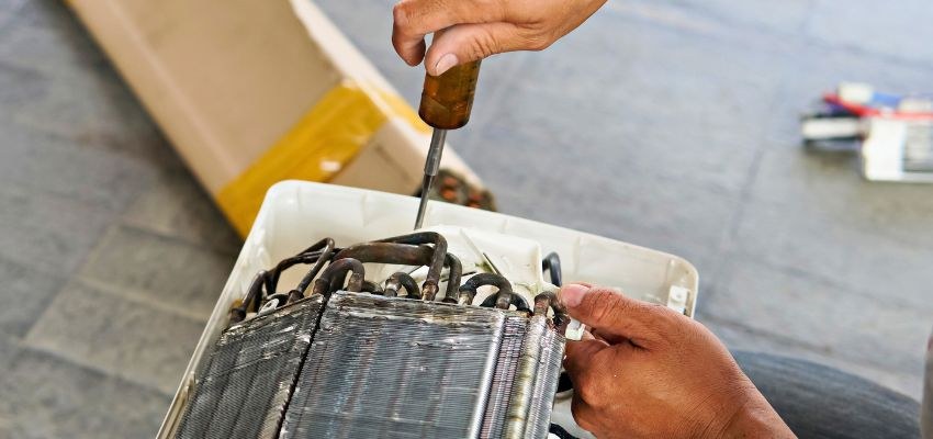 Technician inspecting an air conditioner coil and drain area.