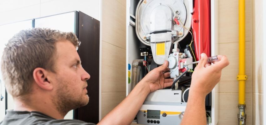 Technician repairing a furnace during a heating service call.