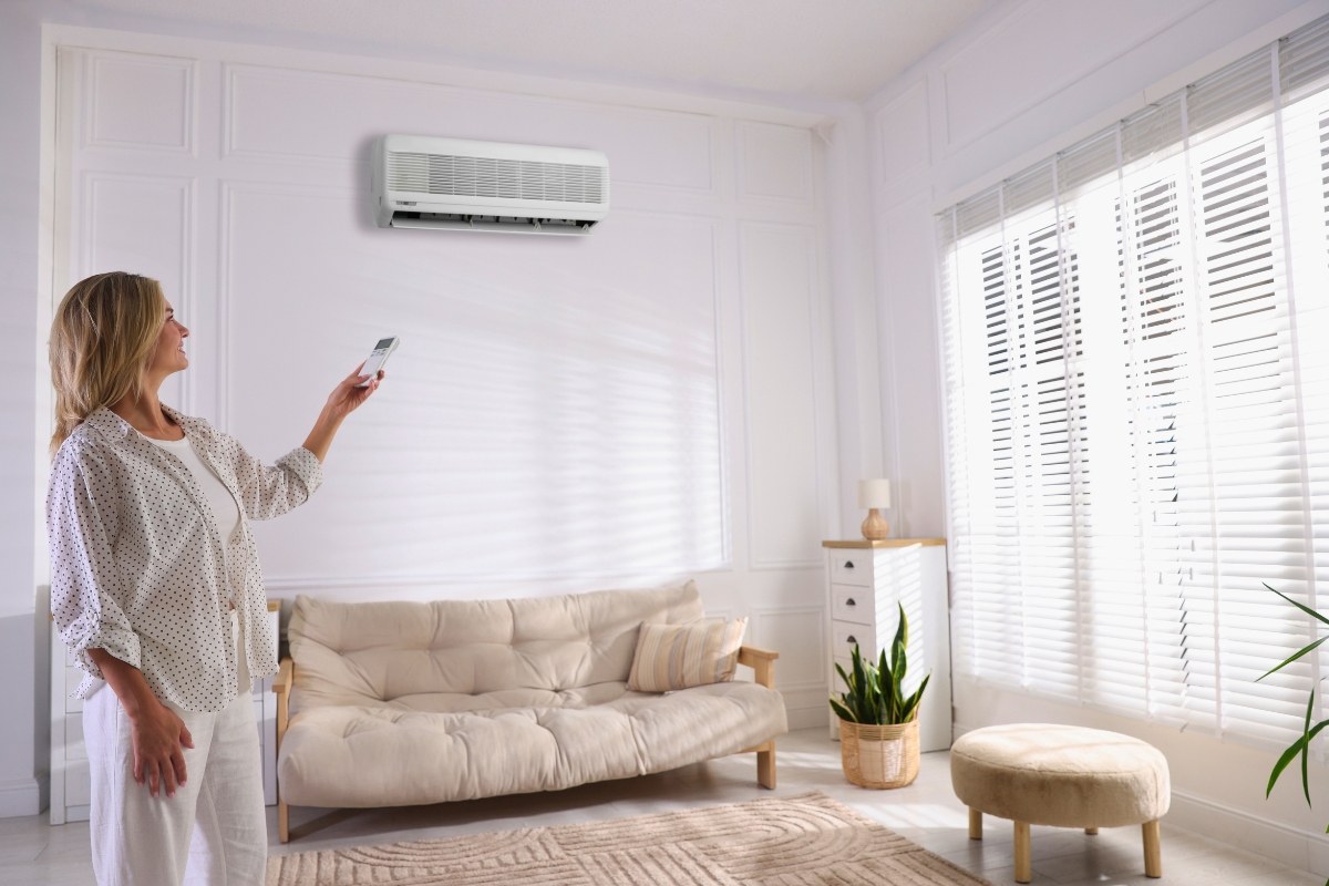 Woman using remote to control indoor air conditioning unit as part of an ERV system