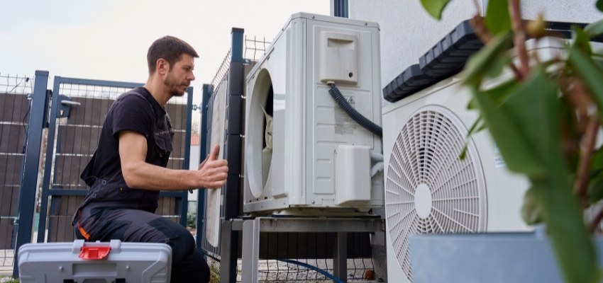 Technician installing or servicing outdoor HVAC units for an ERV system