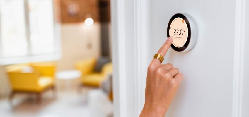 Furnace maintenance with a hand adjusting a smart thermostat to 22.0°C in a modern home