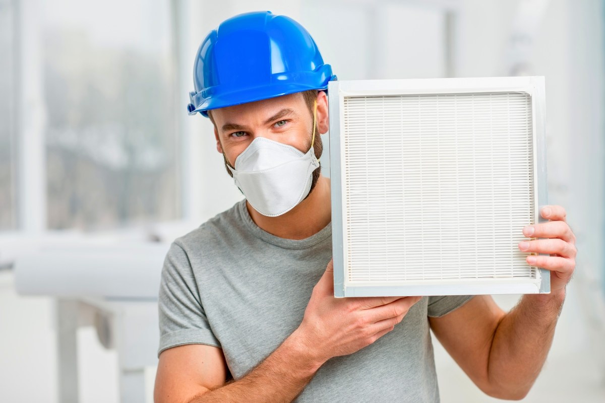Smiling technician holding a clean HVAC filter, reminding homeowners how often to change hvac filter for optimal performance.