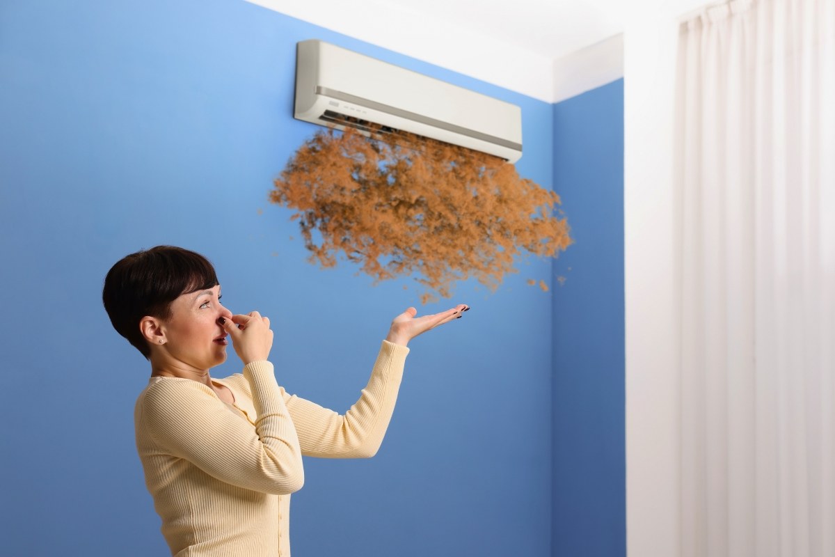 Woman reacting to debris from a unit, a clear warning of mold in air conditioner