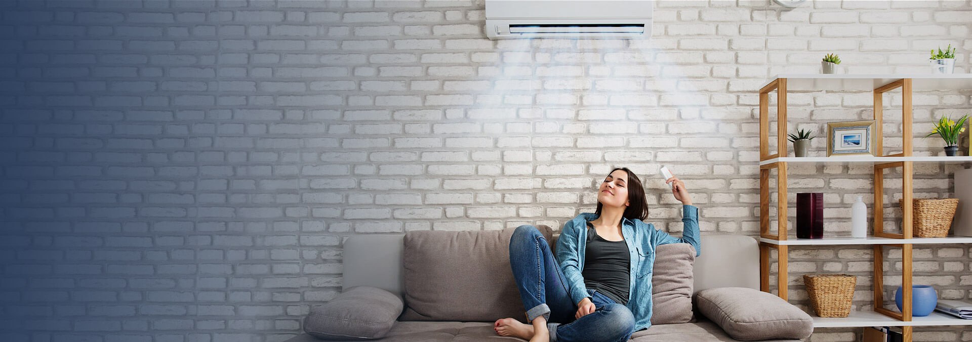The woman is comfortable sitting on the sofa at home because her house is cool even in the summer.