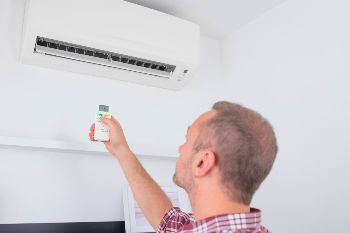 Man using a remote to check his air conditioner while wondering why is my ac not working