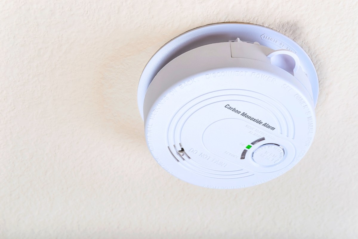 Bottom view of a circular carbon monoxide alarm installed on the ceiling, helping homeowners understand why is my carbon monoxide detector beeping