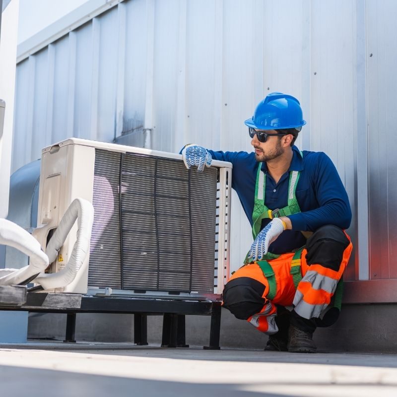 HVAC technician performing maintenance on a commercial rooftop air conditioning system