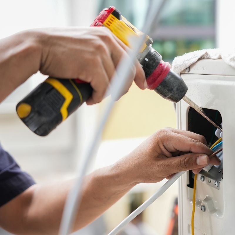 HVAC technician wiring the electrical connections on an air conditioning unit