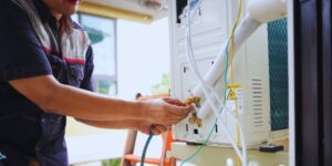 Technician installing and wiring a ductless air conditioning unit, illustrating what is a ductless AC in home cooling systems.