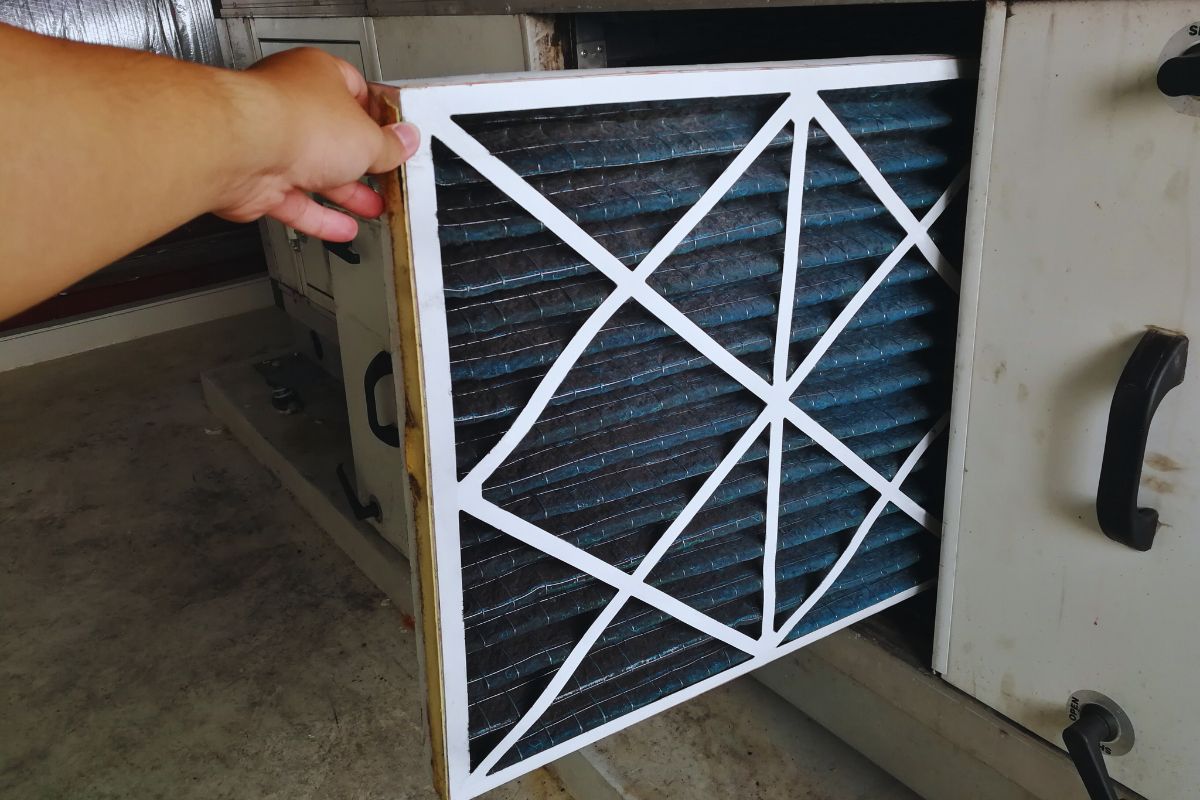Person installing a high-efficiency furnace filter, demonstrating different hvac filter types for indoor air quality control.