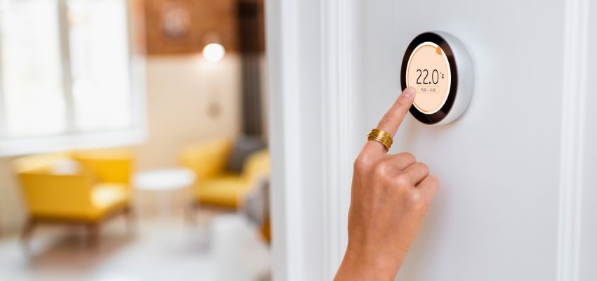 Furnace maintenance with a hand adjusting a smart thermostat to 22.0°C in a modern home