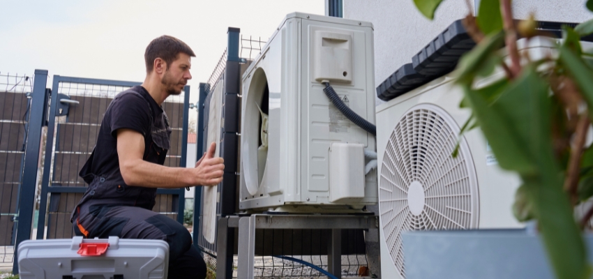 Technician installing or servicing outdoor HVAC units for an ERV system