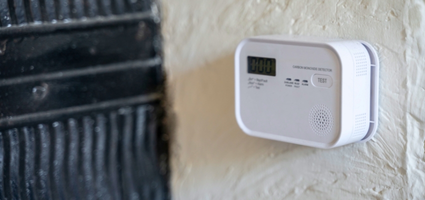 Close-up of a white carbon monoxide detector mounted on a wall showing a digital display, commonly associated with the question why is my carbon monoxide detector beeping