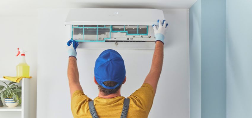Professional technician servicing a wall-mounted AC unit to resolve issues when your ac making noise