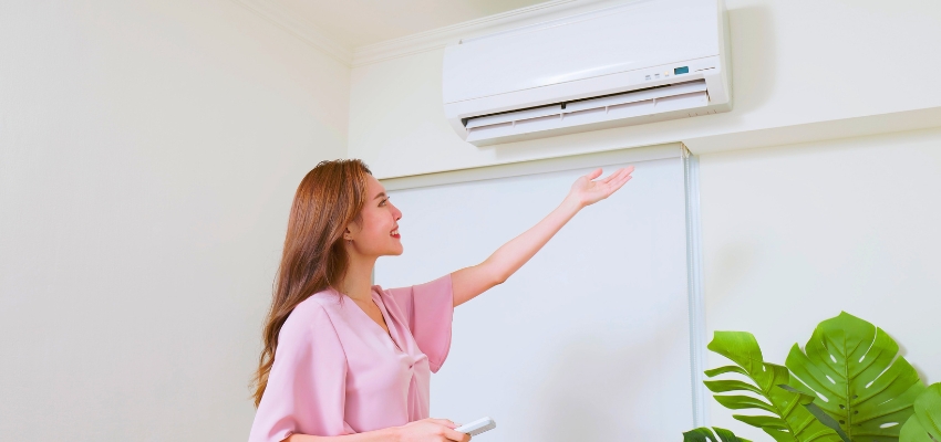 Happy woman enjoying cool air from a wall-mounted mini split, illustrating the comfort that makes many ask are mini splits worth it.