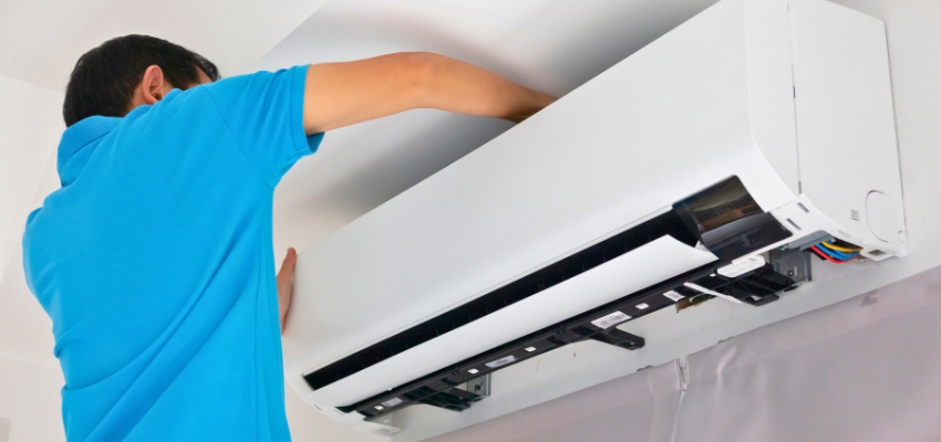 Technician working on a wall-mounted air conditioner, addressing problems causing ac breaker keeps tripping.