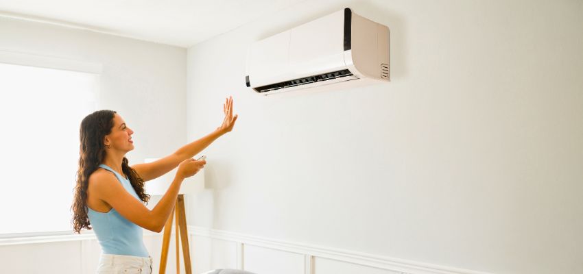 Homeowner checking cool air from a wall unit after addressing an ac refrigerant leak.