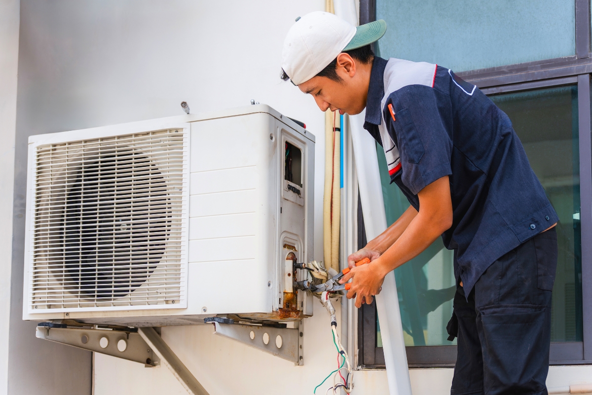 HVAC technician repairing a wall unit, demonstrating practical steps for how to unclog ac drain line.